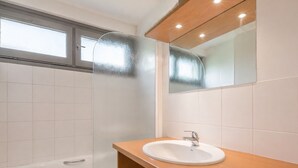 Une salle de bain avec une baignoire, un lavabo et un miroir.
