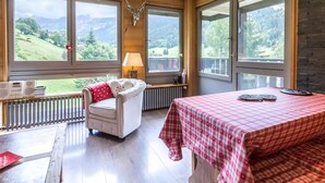 Une chambre comprenant un lit, une chaise, une table et de grandes fenêtres donnant sur une vue imprenable sur les montagnes.