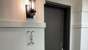 A hallway with a textured wall, a door with a keypad lock, and a wall-mounted light fixture. - Inviting Ski In/Ski Out Condo. Covered Parking. Renovated! Heated Pool/Hot Tubs! (Park City)