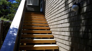 Un escalier en bois mène à un bâtiment dont l’extérieur est recouvert de bardeaux.