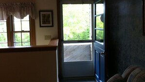 Une pièce avec une porte donnant sur un balcon, une fenêtre avec un rideau et un tableau encadré au mur.
