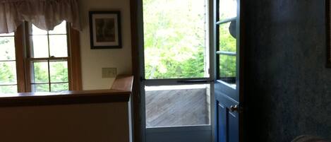 A room with a door leading to a balcony, a window with a curtain, and a framed picture on the wall.