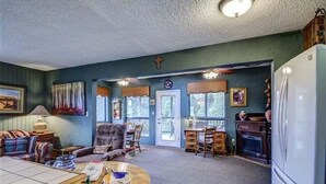 Una sala de estar con chimenea, un comedor y una zona de cocina.