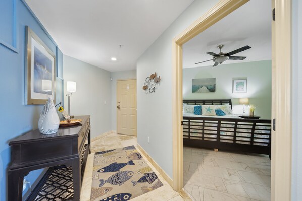 A hallway with a patterned rug, a dark console table, and a ceiling fan. - Luxury Corner Unit For The Discriminating Traveler with Double Beach Service (Navarre)