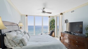 A bedroom with a bed, a dresser, a television, and a view of the ocean. - Luxury Corner Unit For The Discriminating Traveler with Double  Beach Service (Navarre)