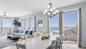 A spacious living room with a large dining table, a sofa set, and a view of the beach. - Luxury Corner Unit For The Discriminating Traveler with Double  Beach Service (Navarre)