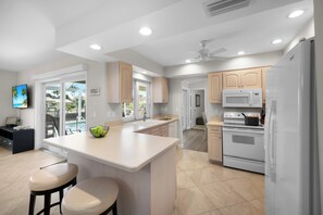 A modern kitchen with white cabinets, a central island, and a built-in oven.