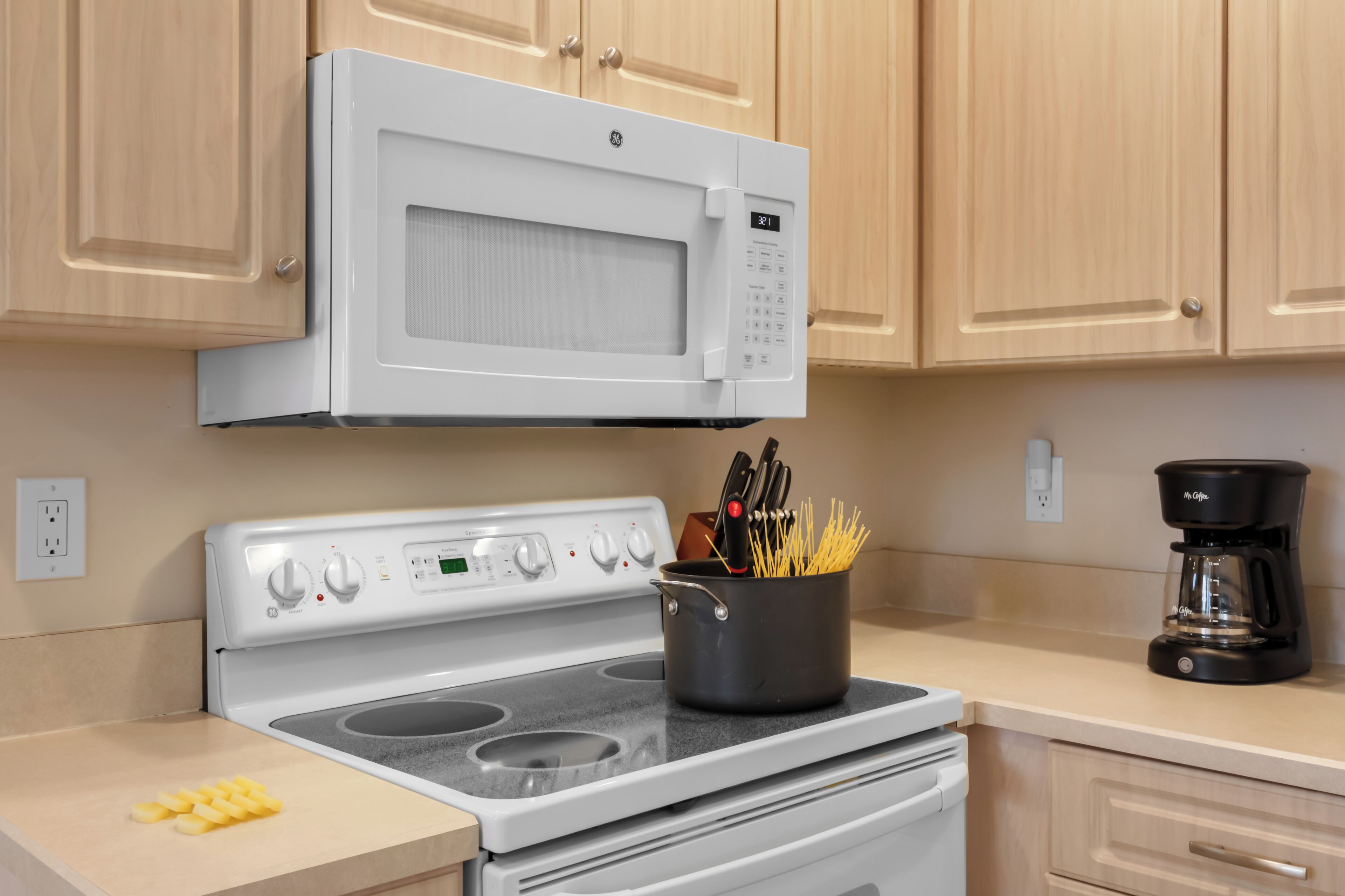 Une cuisine avec un four à micro-ondes blanc, une cuisinière et une machine à café.