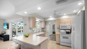 A modern kitchen with white cabinets, a central island, and a built-in oven. - Idyllic Waterfront Home | Pool & Western Exposure (Marco Island)
