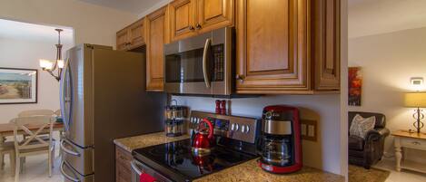 A modern kitchen with stainless steel appliances, wooden cabinets, and granite countertops.
