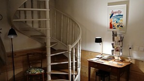 A cozy room with a spiral staircase, a wooden desk, a chair with a floral cushion, and a poster on the wall. - Warm family home (Ménétréol-sous-Sancerre)