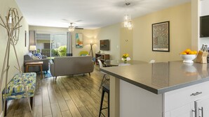 A modern kitchen with a central island, a dining area with a sofa and chairs, and a living room with a couch and a coffee table.