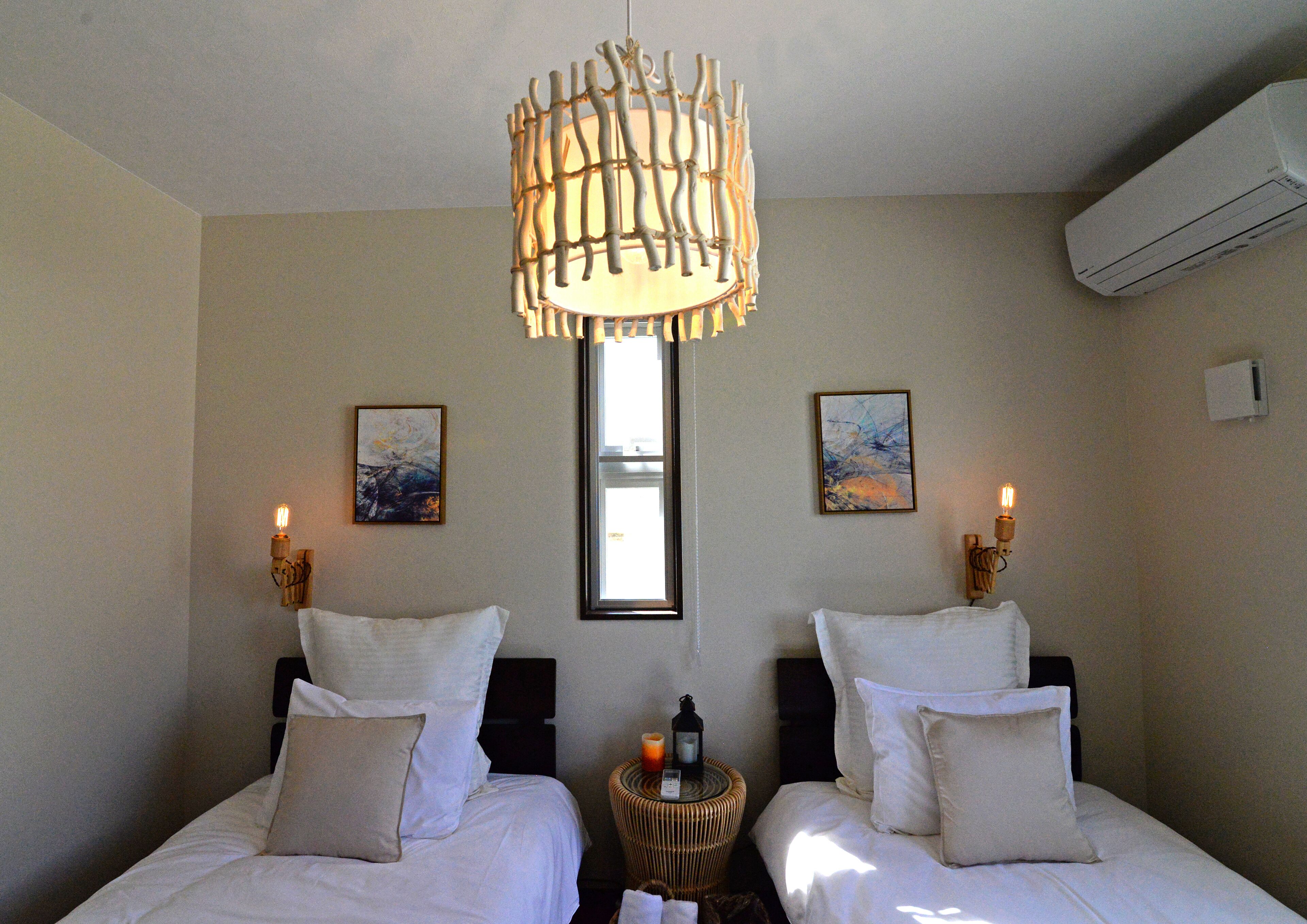 A hotel room with two beds, a large window, and a unique hanging light fixture.