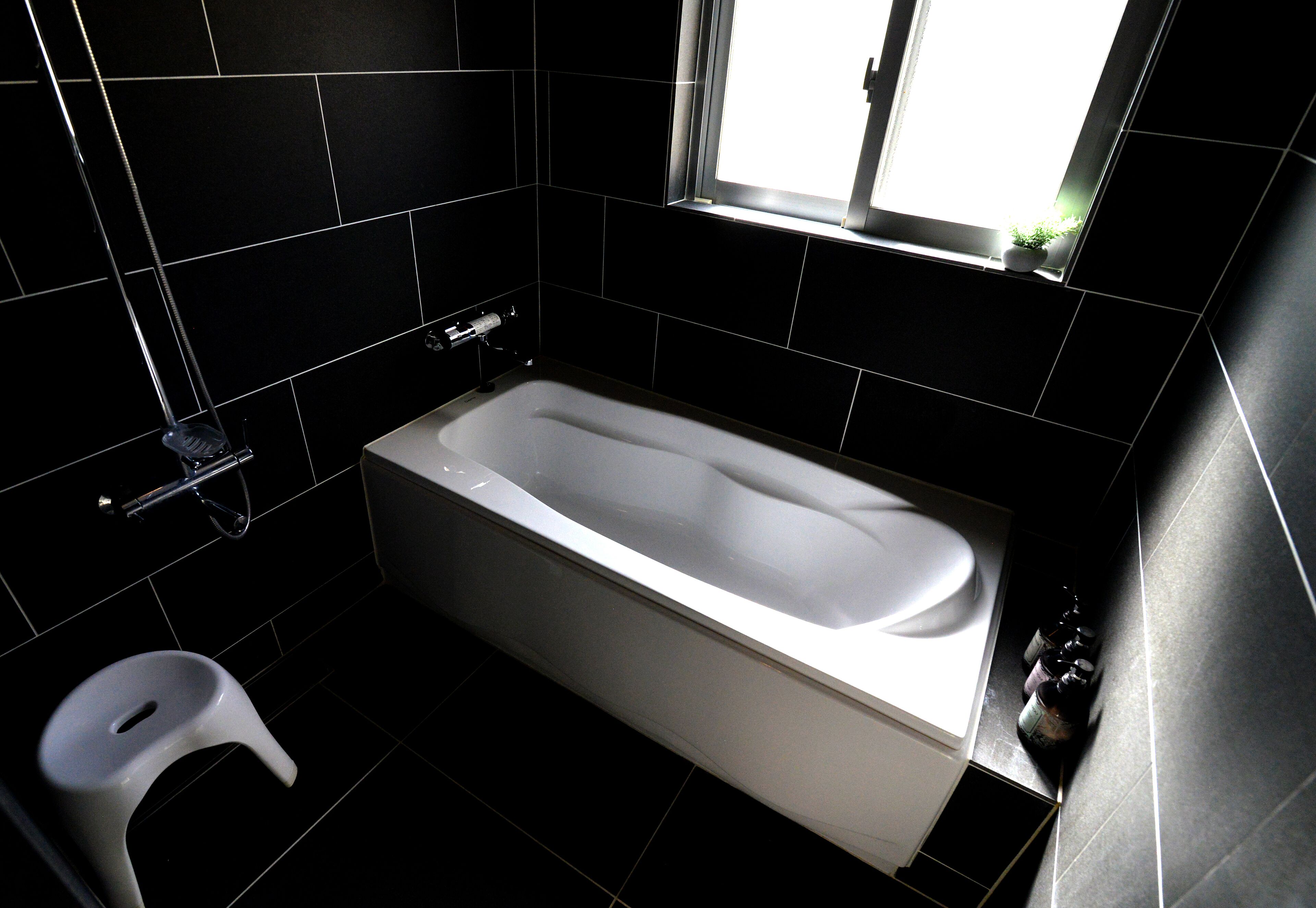 A modern bathroom with a bathtub, a toilet, and a window providing natural light.