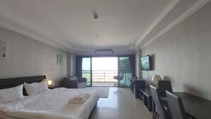 Une chambre d’hôtel avec un grand lit, un bureau, une chaise, une télévision et un balcon avec vue.