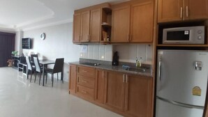 Une cuisine moderne avec des meubles en bois, un four à micro-ondes encastré et un réfrigérateur en acier inoxydable.