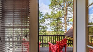 A wooden deck with red Adirondack chairs, a view of trees and a cloudy sky. - Wild Horse Lodge | Galloping Good Times Retreat w/ Game room Fun & Spacious Living (Alto)