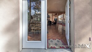 A sliding glass door leading to an outdoor patio area with a tiled floor and a patterned rug. - Wild Horse Lodge | Galloping Good Times Retreat w/ Game room Fun & Spacious Living (Alto)