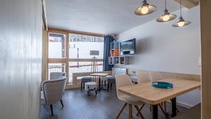 Un interior moderno con una mesa de comedor de madera, sillas y lámparas colgantes.