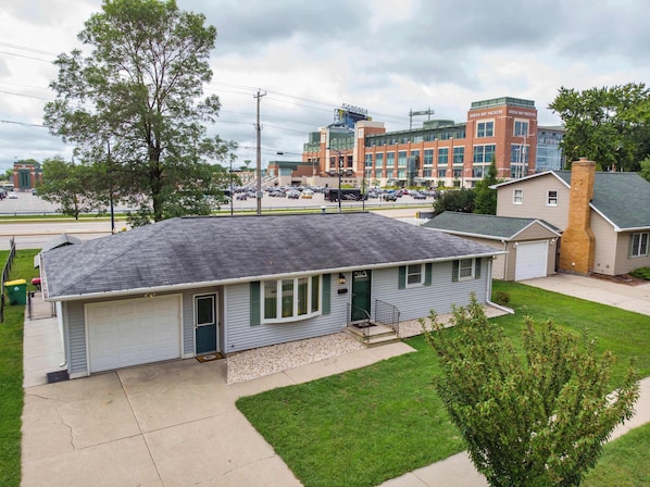 A residential house with a garage, a front yard, and a driveway. - Game Day HQ w/ Fan Cave, Fire Pit + Stadium Views (Green Bay)