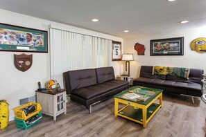 A living room with two couches, a coffee table, and sports memorabilia on the walls.
