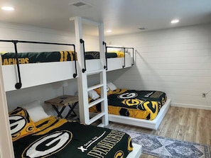 A room with bunk beds, a small table, and a rug.