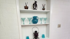 A white brick wall with a white cabinet containing decorative items.