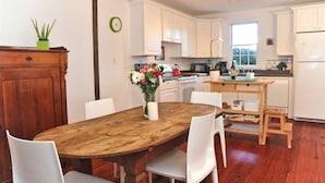 Una cocina moderna con armarios blancos, una mesa de comedor de madera y un ventanal.