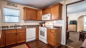 A compact kitchen with wooden cabinets, a white microwave, and a stove.