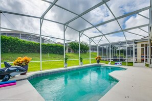 Ein überdachter Pool mit Blick auf einen Rasen und ein Haus im Hintergrund.