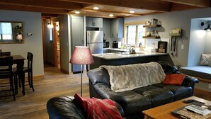 A cozy living room with a leather sofa, a coffee table, and a dining area with chairs.