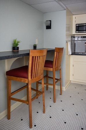 Compact kitchen with central island, stainless steel oven, and microwave, perfect for cooking and dining.