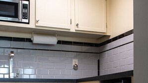A kitchen with cream-colored cabinets, a stainless steel refrigerator, and a microwave.