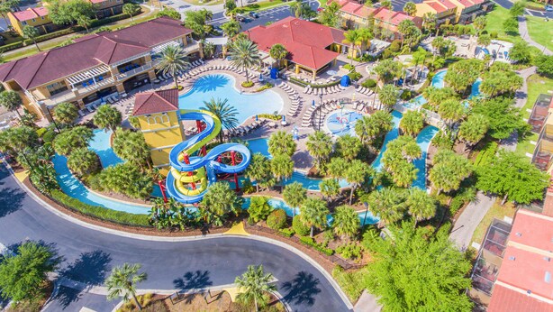 An aerial view of a resort with a central pool area, multiple water slides, and surrounding greenery. - Orlando Villa Close to Disney and Free Water Park (Kissimmee)