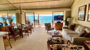A spacious living area with a balcony overlooking the sea, furnished with a sofa, chairs, and a coffee table. - Stunning Beach Front Townhouse (Kihei)