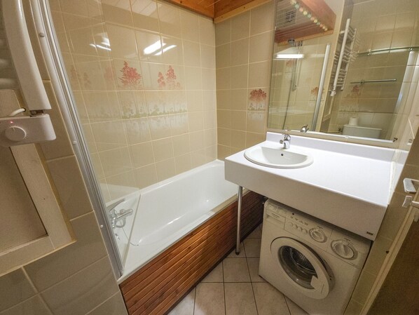 A bathroom with a bathtub, a sink, and a washing machine.