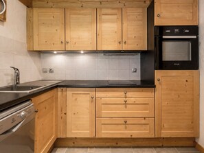 A kitchen with wooden cabinets, a stainless steel sink, a built-in oven, and a dishwasher.