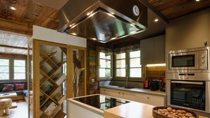 Una cocina moderna con electrodomésticos de acero inoxidable, techo de madera y una división de vidrio.