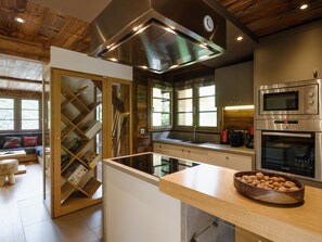 A modern kitchen with stainless steel appliances, a wooden ceiling, and a glass partition. - 5* Modern Chalet, Near Slopes, Garage, WIFI (La Clusaz)