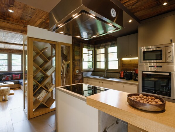 A modern kitchen with stainless steel appliances, a wooden ceiling, and a glass partition.
