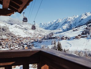 A ski resort with a chairlift, snow-covered buildings, and mountains in the background.