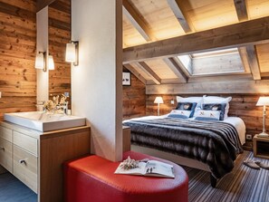 A cozy bedroom with a wooden ceiling, a large bed with multiple pillows, a red bench, and a skylight. - 5* Modern Chalet, Near Slopes, Garage, WIFI (La Clusaz)