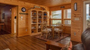 A wooden cabin interior with a dining area, shelves with various items, and a clock on the wall. - Teton Riverfront Retreat | Spacious, Peaceful, Perfect for Family Adventures (Victor)
