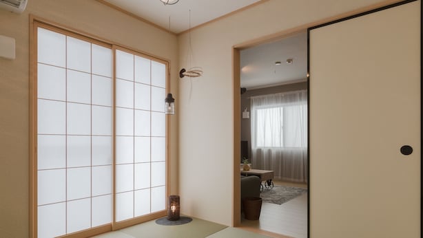 Een traditionele Japanse kamer met tatami vloerbedekking, shoji schermen en een schuifdeur.