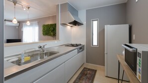 Een moderne keuken met een RVS spoelbak, een inbouwfornuis, een magnetron en een koelkast.