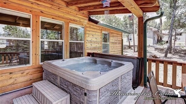 Eine Holzhütte mit Whirlpool, großen Fenstern und einer amerikanischen Flagge.