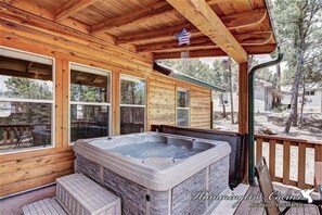 Une cabane en bois avec un jacuzzi, de grandes fenêtres et un drapeau américain.
