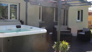 Ein Whirlpool unter einer Pergola mit Außenmöbeln.