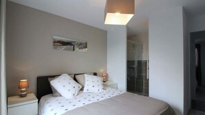 Ein Schlafzimmer mit einem Bett, zwei Nachttischen mit Lampen, einem Wandbild und einer Duschkabine.