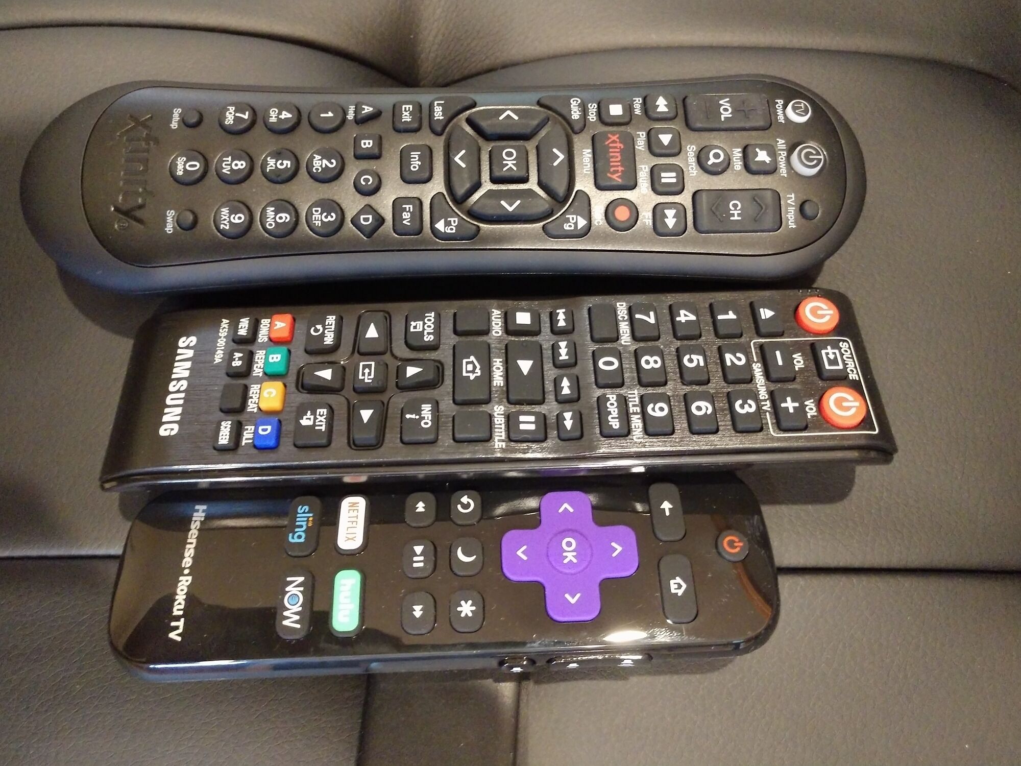 Three remote controls on a black surface.